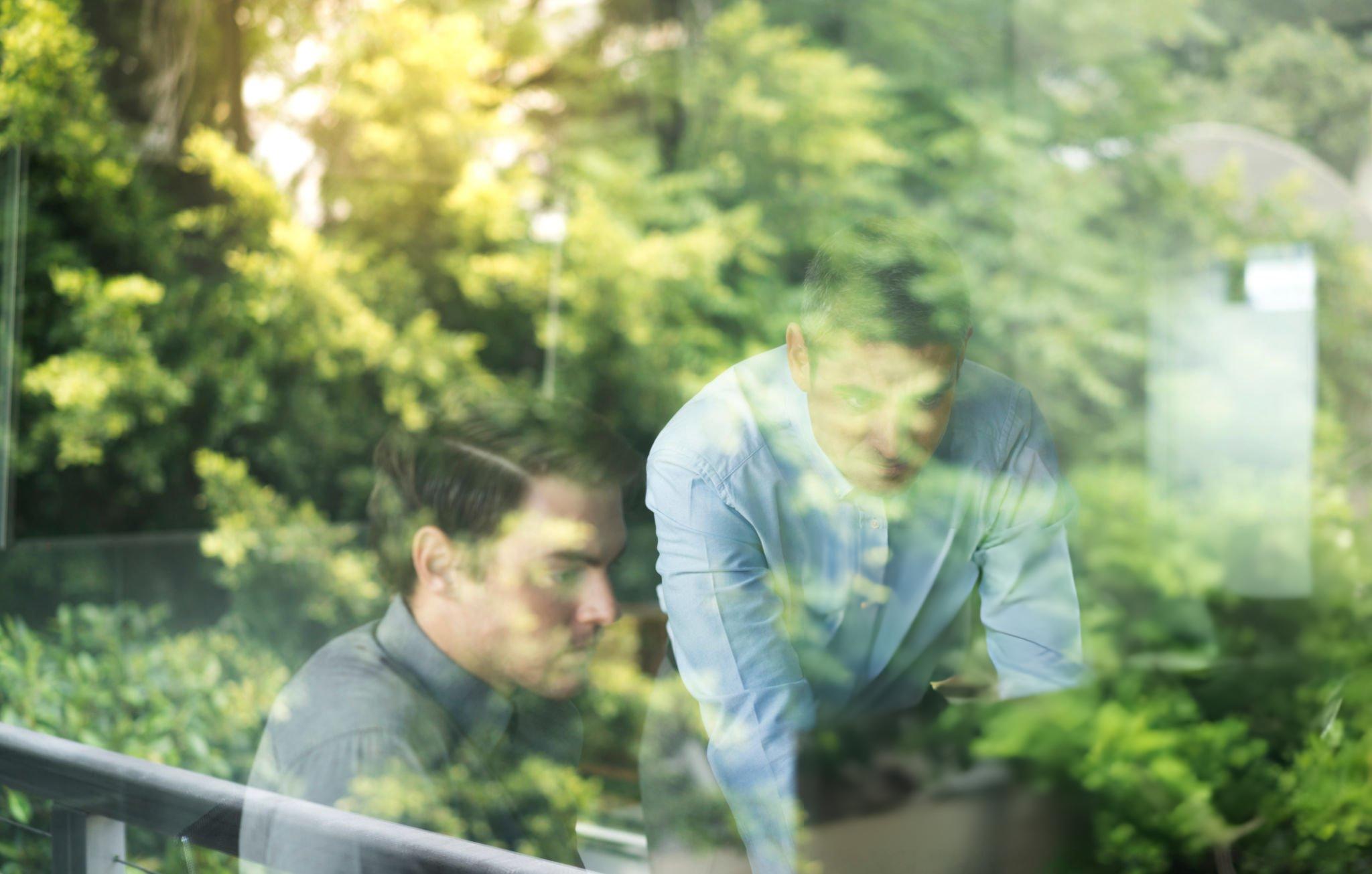 Due professionisti al lavoro dietro una vetrata affacciata sul verde