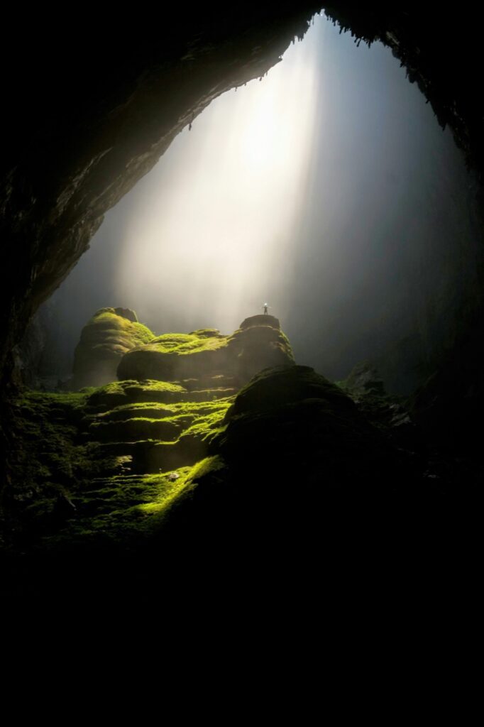 Figura in cima a una roccia in una grotta illuminata dall’alto